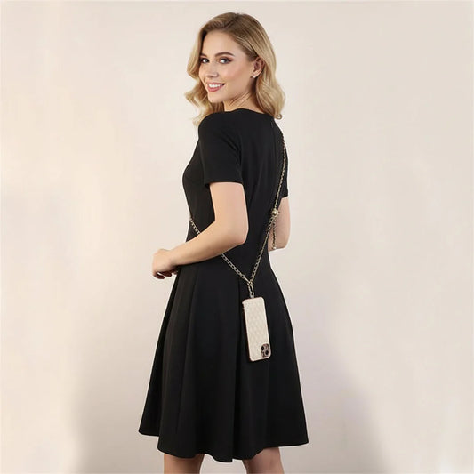 Woman wearing a black dress with a crossbody phone on a plain background