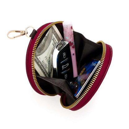 Small red pouch with gold zipper containing money, keys, and a phone on a white background