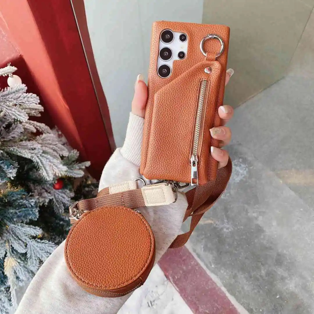 Person holding a brown wallet phone case with a keychain and round pouch in front of a Christmas tree.