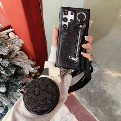 Person holding a black phone case with a round pouch, Christmas tree in the background