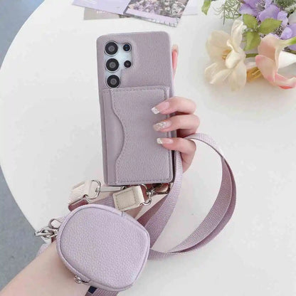 Hand holding a pastel purple phone case with a matching pouch and strap on a white surface with flowers.