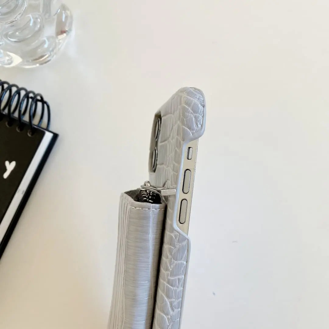 Silver phone case with crocodile texture on a white surface