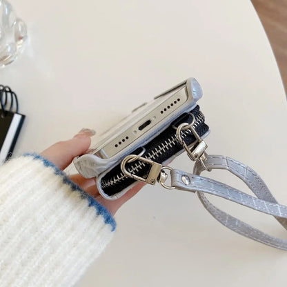 Phone case with a zipper and cross body strap held by a hand on a light background