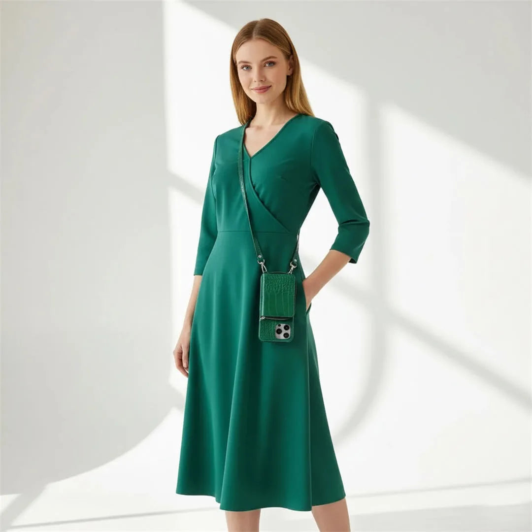 Woman wearing a green dress with a matching crossbody wallet case on a white background