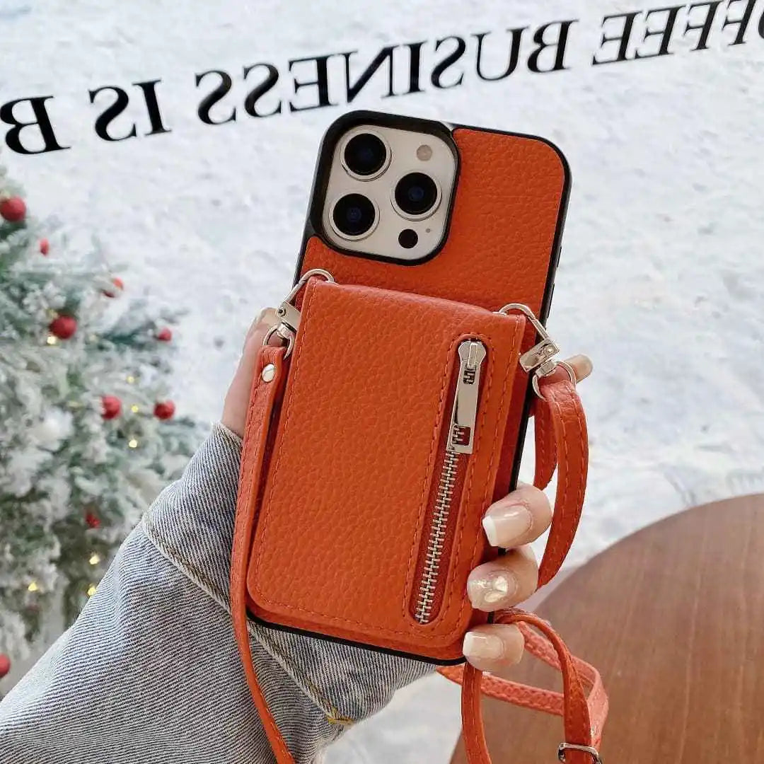Orange leather phone case with a strap held by a hand, Christmas tree in the background