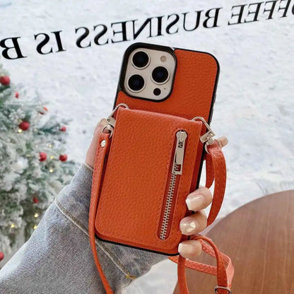 Orange leather phone case with a strap held by a hand, Christmas tree in the background