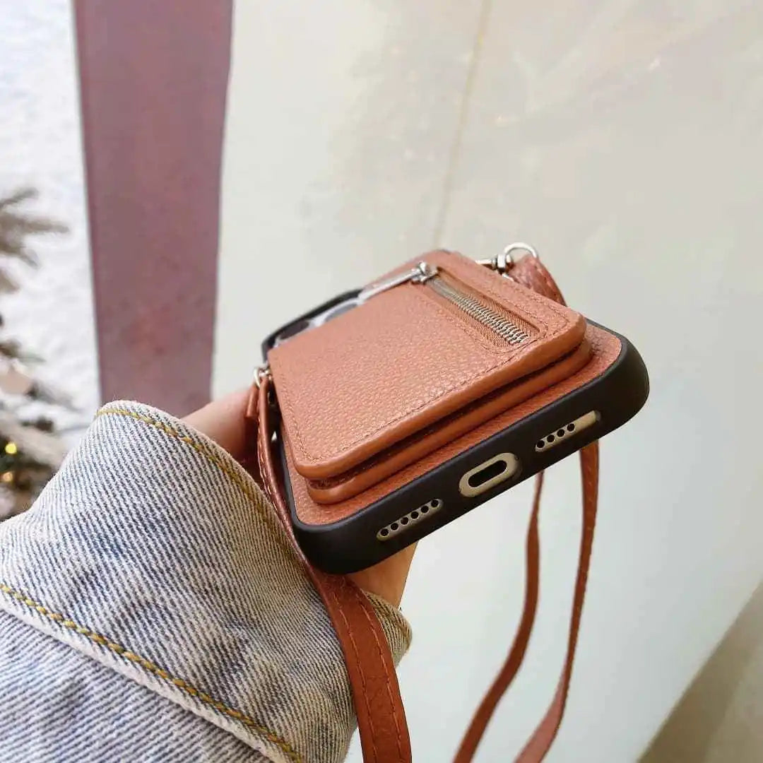 Brown leather phone case with strap held by a person wearing jeans.