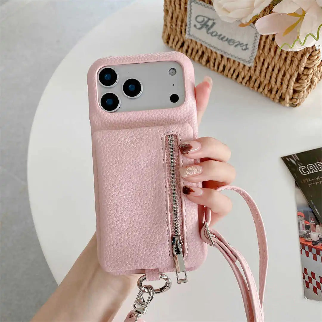 Pink phone case with wallet and a strap held by a hand on a light background