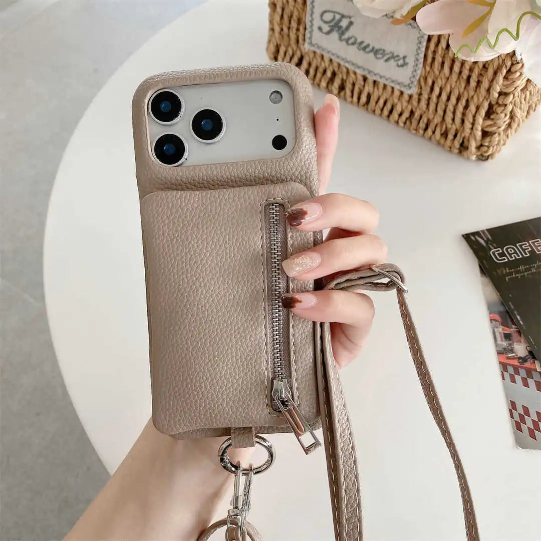tan phone case with a strap and wallet held by a hand on a light surface. 
