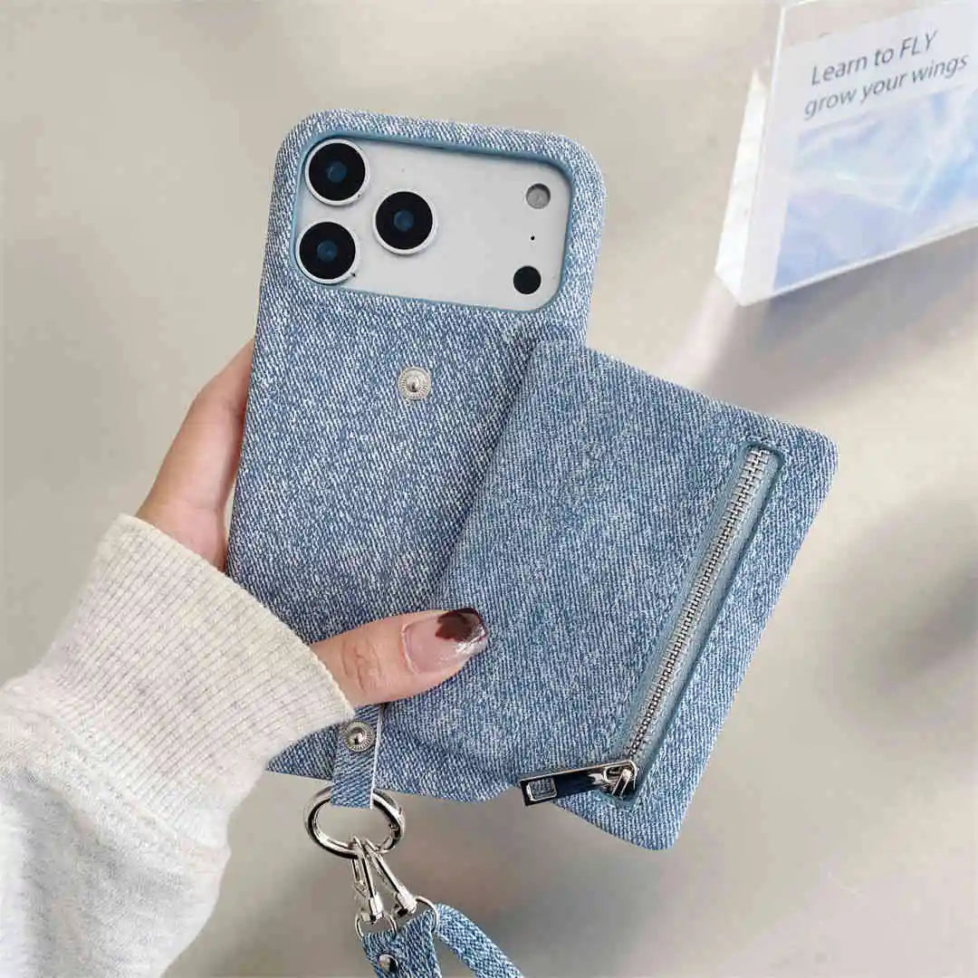 Blue denim-style phone case with a zipper wallet and strap held by a hand on a light background