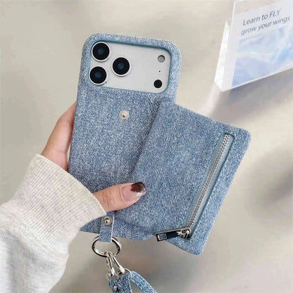 Blue denim-style phone case with a zipper wallet and strap held by a hand on a light background