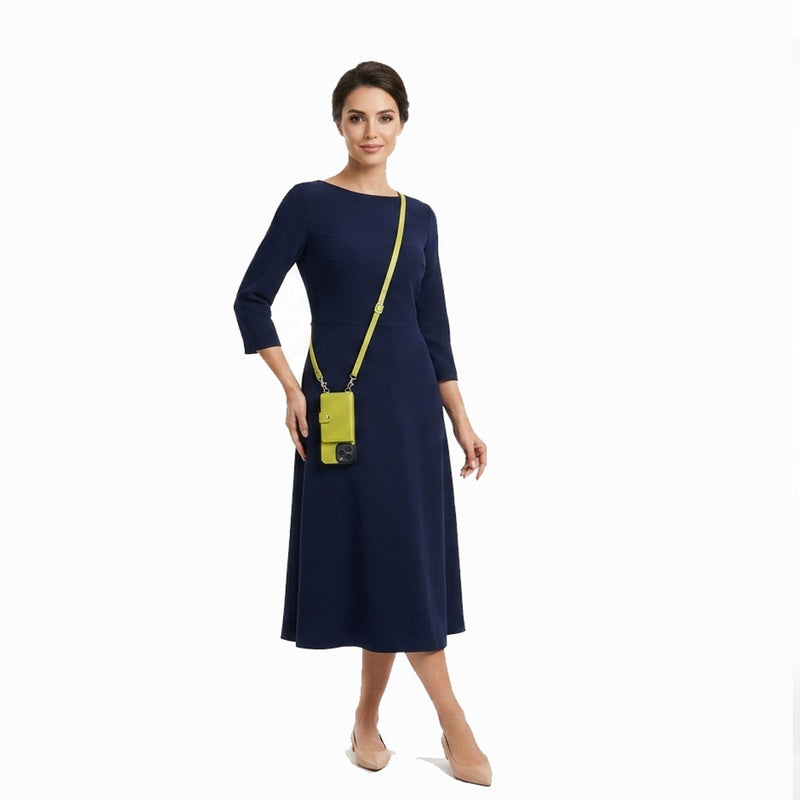 Woman wearing a navy dress with a yellow crossbody phone case on a white background
