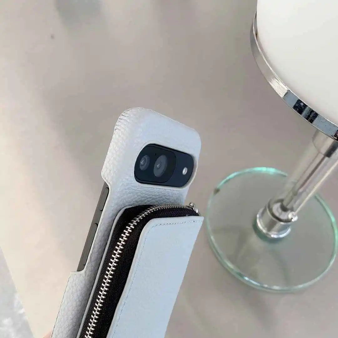 Close-up of a phone case with a camera lens, held by a hand against a neutral background.