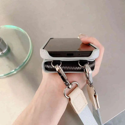 Phone case with a strap held by a hand on a neutral background
