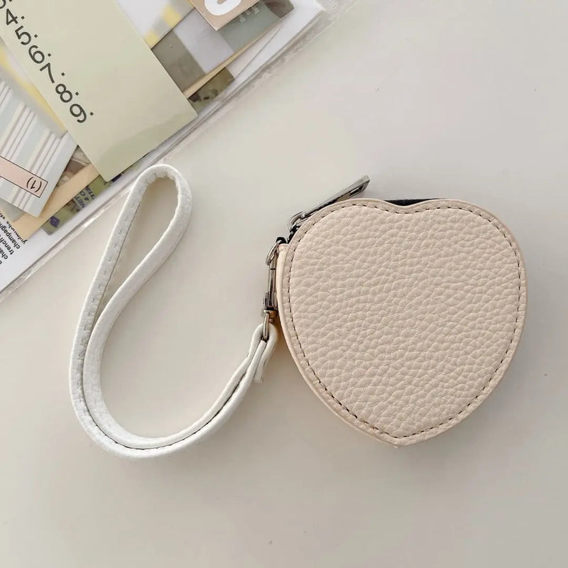 Heart-shaped ivory coin pouch with a strap on a light surface