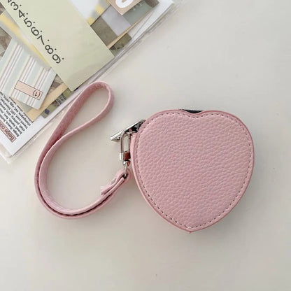 Heart-shaped pink pouch with a strap on a light surface
