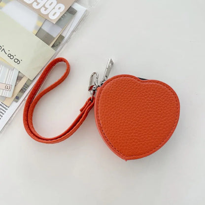 Orange heart-shaped keychain pouch with a strap on a light gray background