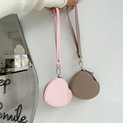 Two heart-shaped Airpods pouch, one pink and one beige, held against a white background.