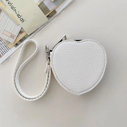 White heart-shaped pouch with strap on a light gray surface