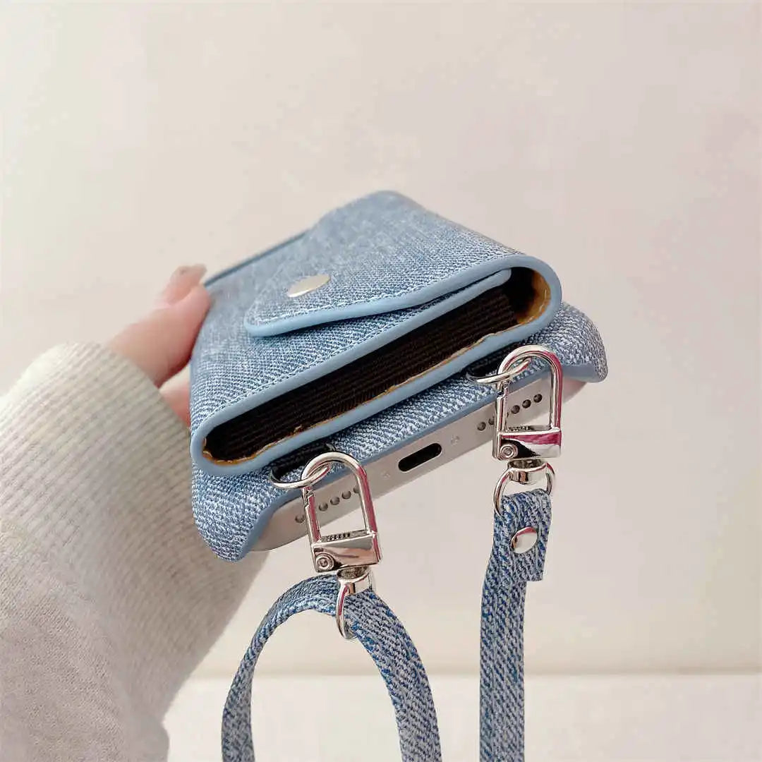 Blue denim phone case with a strap held by a hand against a light background