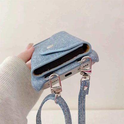 Blue denim phone case with a strap held by a hand against a light background