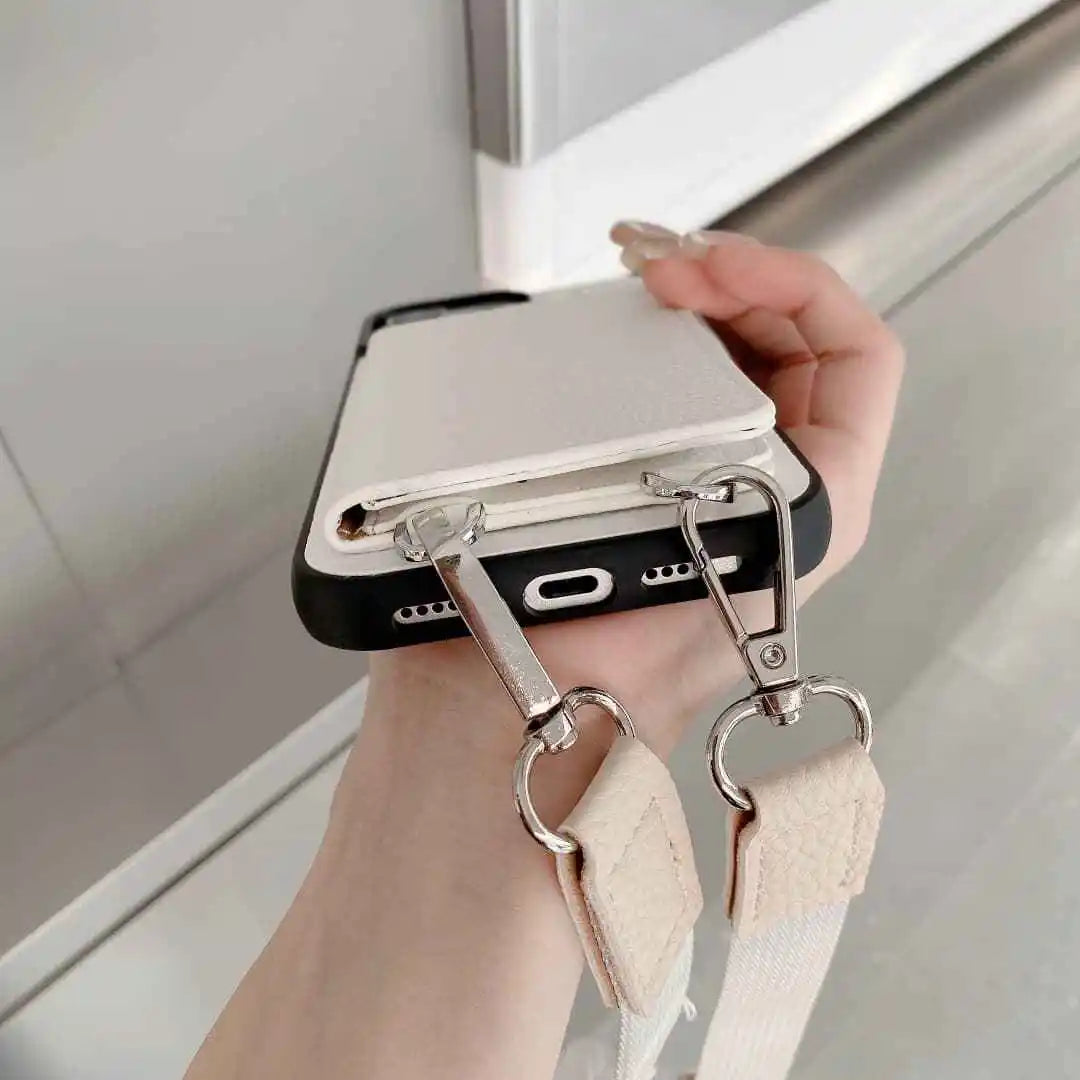 Phone case with a strap held by a hand in front of a mirror.