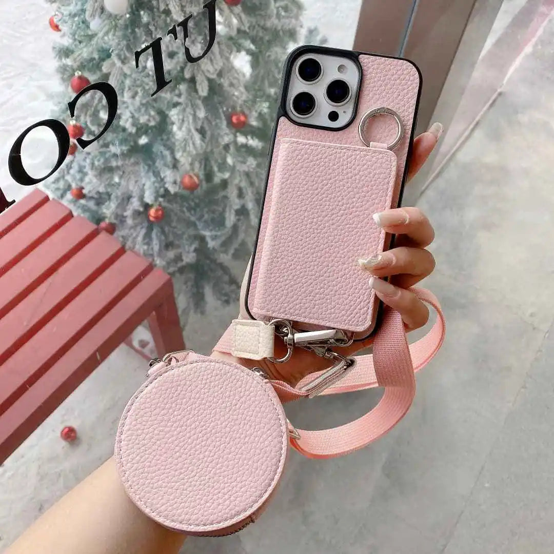 Pink wallet phone case with strap held by a hand, Christmas tree in the background