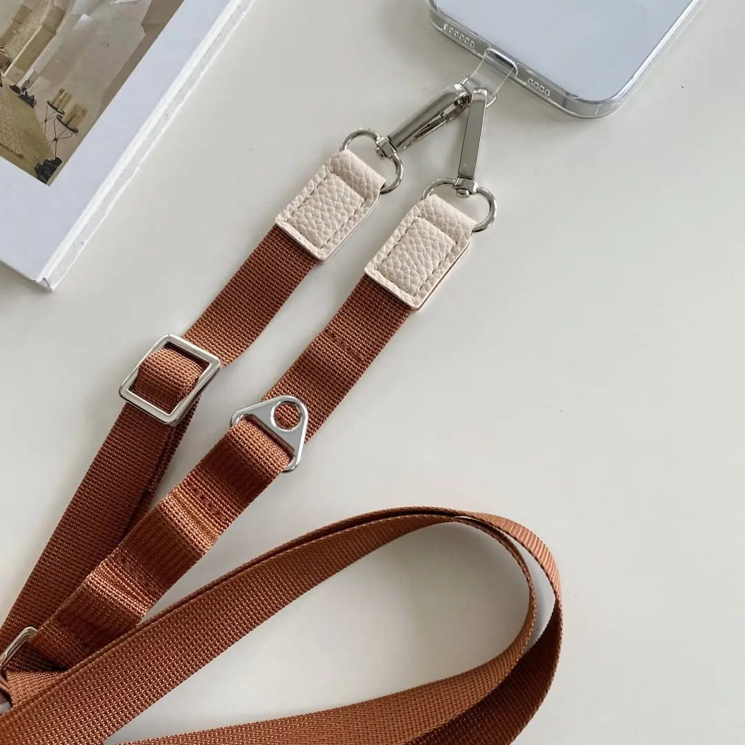 Brown phone strap with metal clasps on a white surface