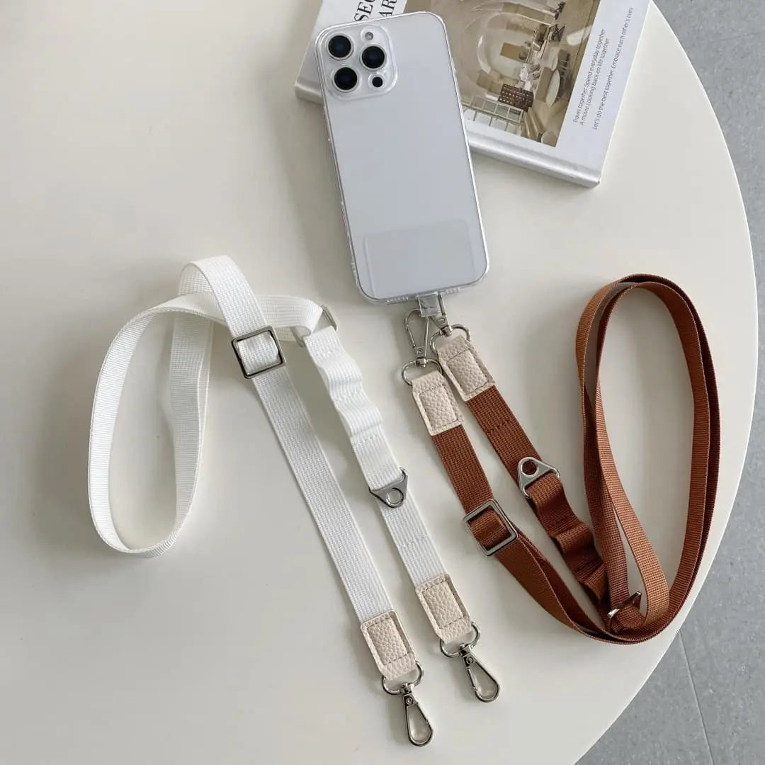Two phone straps, one white and one brown, on a white surface with a phone case.