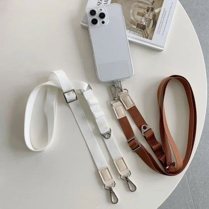 Two phone straps, one white and one brown, on a white surface with a phone case.